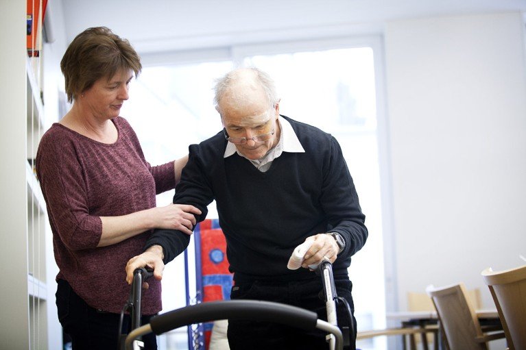 Una cuidadora ayuda a un paciente en un centro de cuidado diurno en Suiza para personas que sufren de la enfermedad de Parkinson.