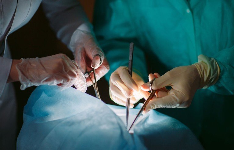 Un primer plano de las manos de cirujanos sosteniendo instrumentos médicos durante una operación quirúrgica.