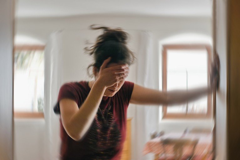 Foto borrosa de una mujer agarrándose la cabeza mientras sufre de una migraña.
