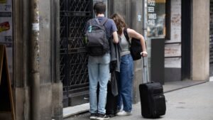 Dos turistas frente a un portal de un piso turistico en Barcelona.