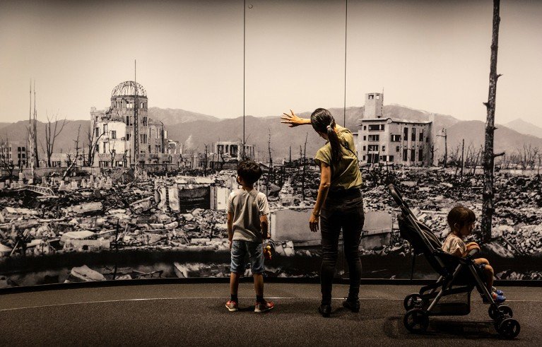 Una madre y dos niños en el Museo de la Paz de Hiroshima observan una gran fotografía del daño causado por la bomba atómica.